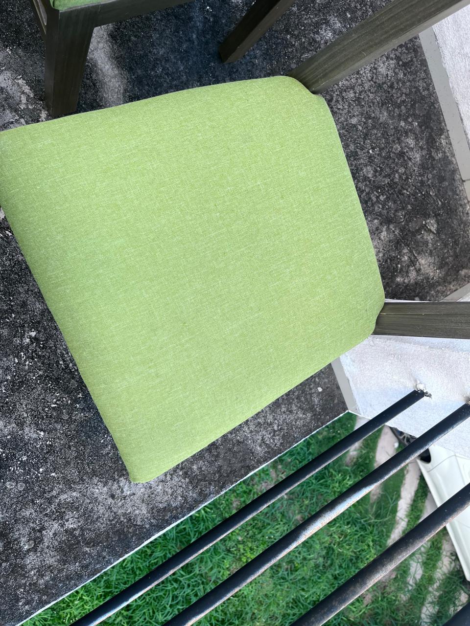 Silla con asiento verde en primer plano, sin manchas visibles.