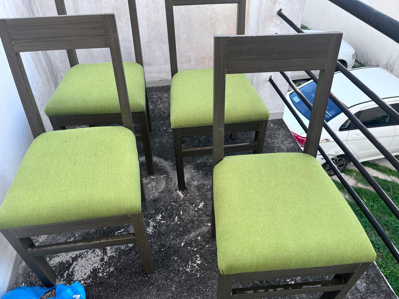 Cuatro sillas con asientos verdes, limpias y alineadas.
