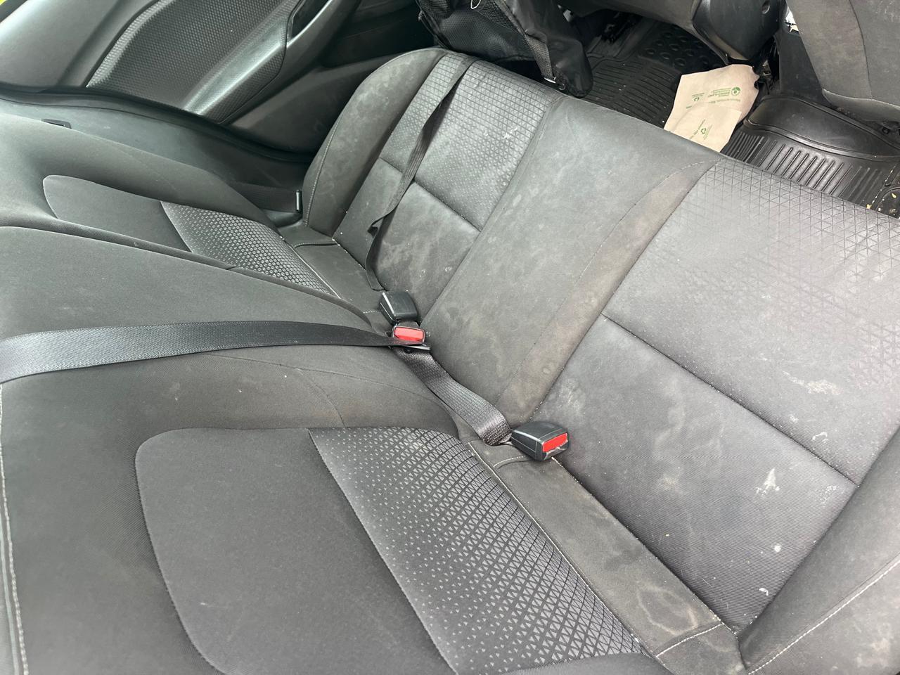 Asiento trasero de automóvil con manchas visibles.